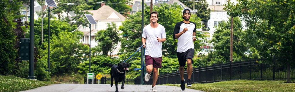 Two men jogging with a dog in Greensboro